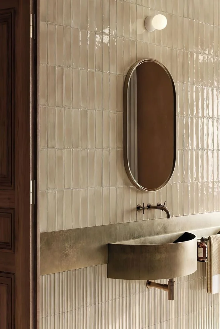 Salle de bains aux tons chauds : zellige, miroir ovale et vasque en métal