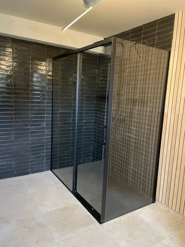 Douche rénovée par Fornillo : carrelage sombre et habillage en lames de bois